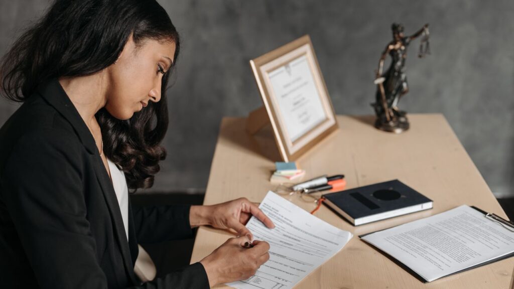 Corporate lawyer reviewing legal compliance documents near a Lady Justice statue representing Swiss FADP criminal liability and GDPR fines