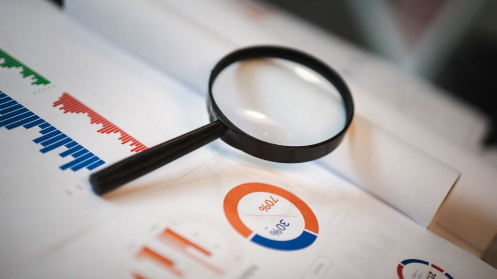 Magnifying glass resting on audit charts and data reports, symbolizing strategic visibility and inspection in an AI model registry.