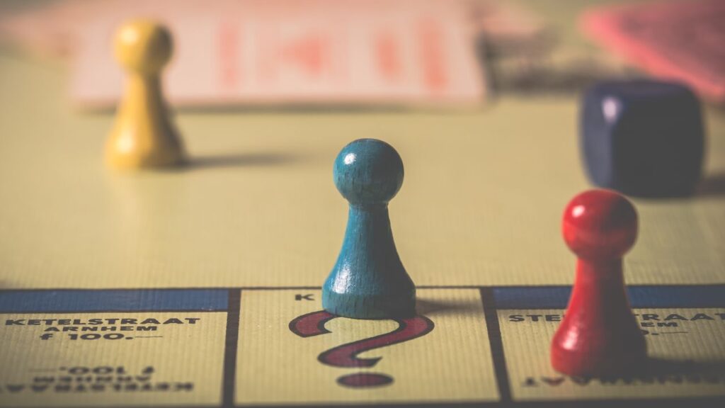 Board game pieces on a game board with a blue pawn resting on a question mark, symbolizing AI decision criticality and risk tiering assessment.